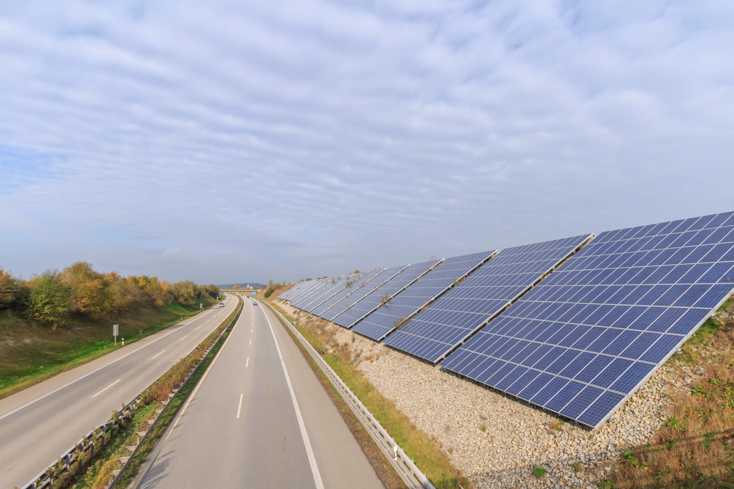 Solar panels installed along a highway slope with anti-glare technology, ensuring efficiency and road safety.