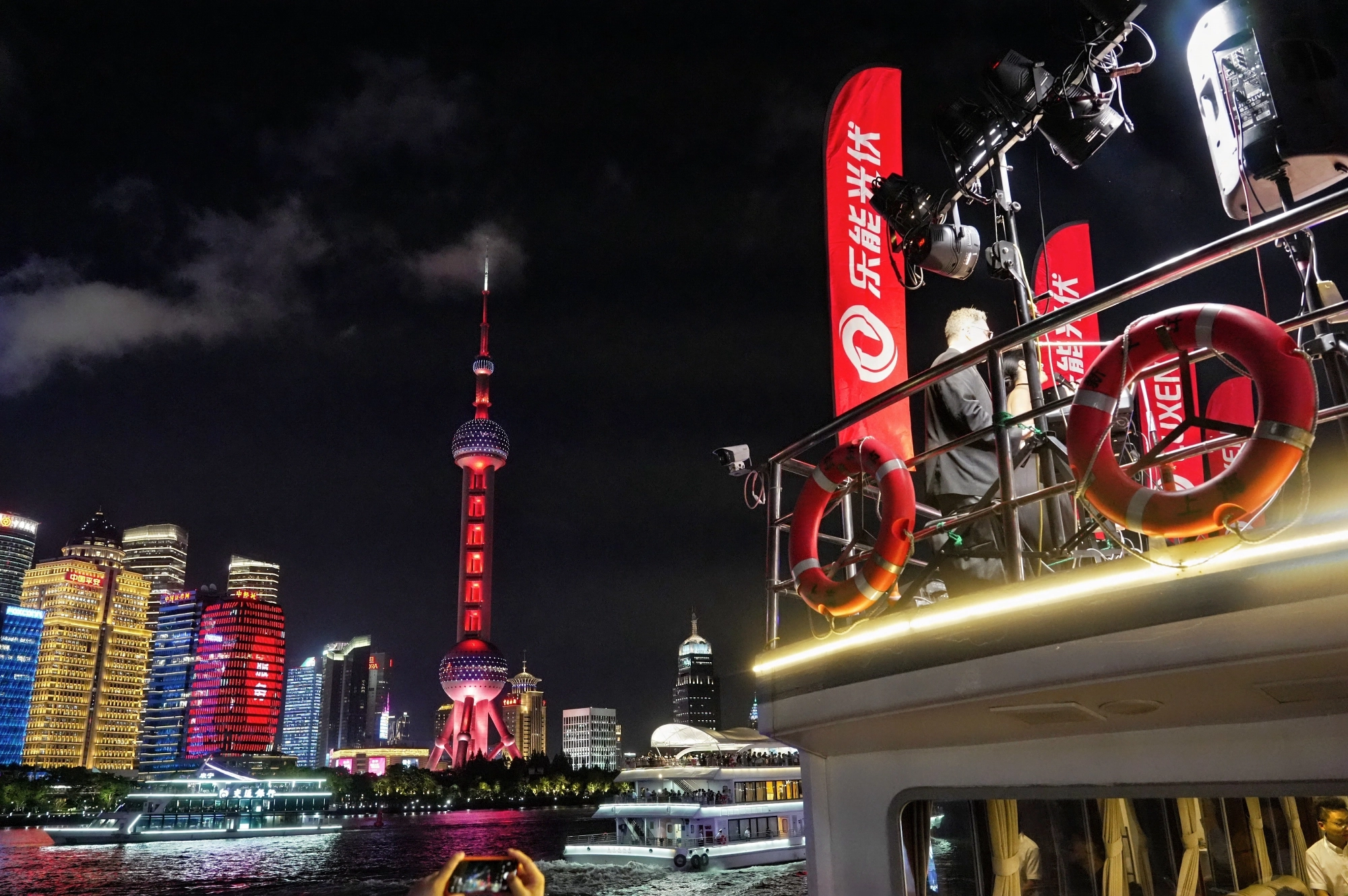 Night view of the Shanghai skyline featuring the Oriental Pearl Tower lit in red, with a Luxen Solar promotional event taking place on a boat in the foreground.